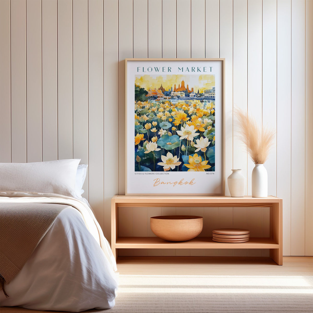 Bangkok flower market print in an oak frame on a wood bench against a white shiplap bedroom wall with pampas grass