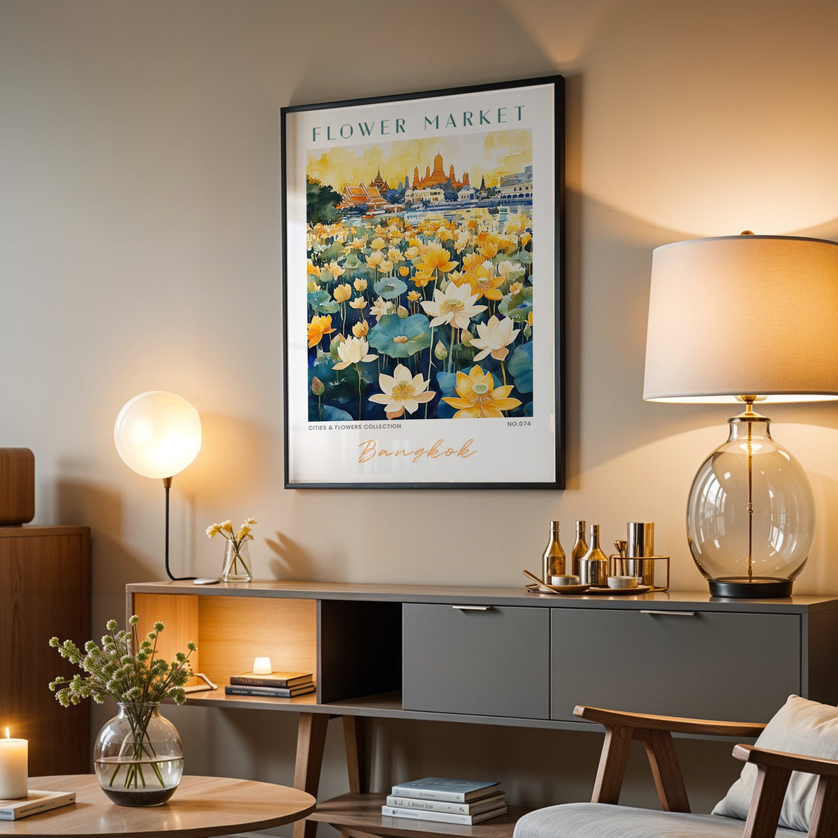 Bangkok flower market print in a black frame above a grey media console with a glass table lamp