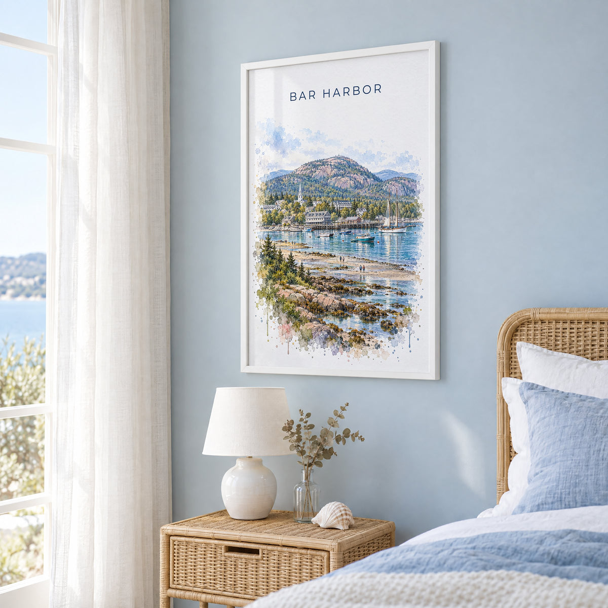 Bar Harbor watercolor print in a white frame on a pale blue wall beside a rattan bed in a coastal bedroom