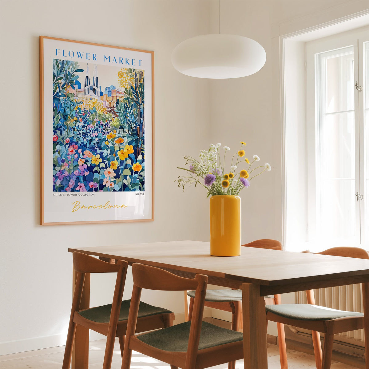 Barcelona flower market print in an oak frame above a dining table with a yellow vase and white pendant light