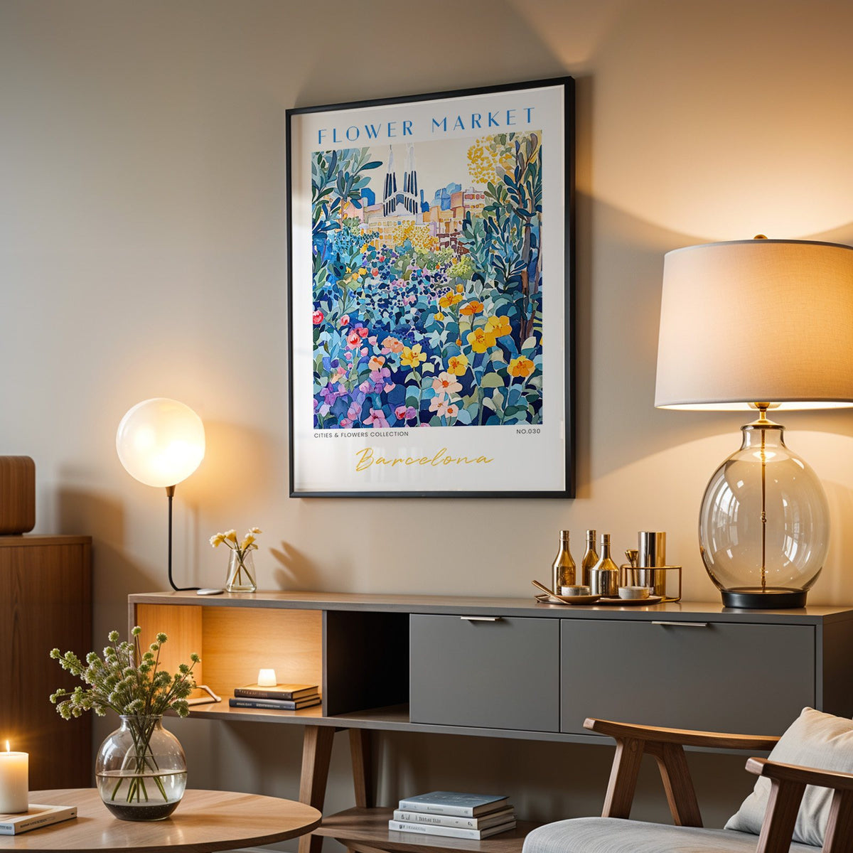 Barcelona flower market print in a black frame above a grey media console with a glass table lamp