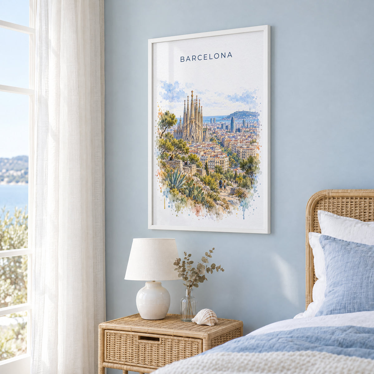 Barcelona watercolor print in a white frame on a pale blue wall beside a rattan bed in a coastal bedroom