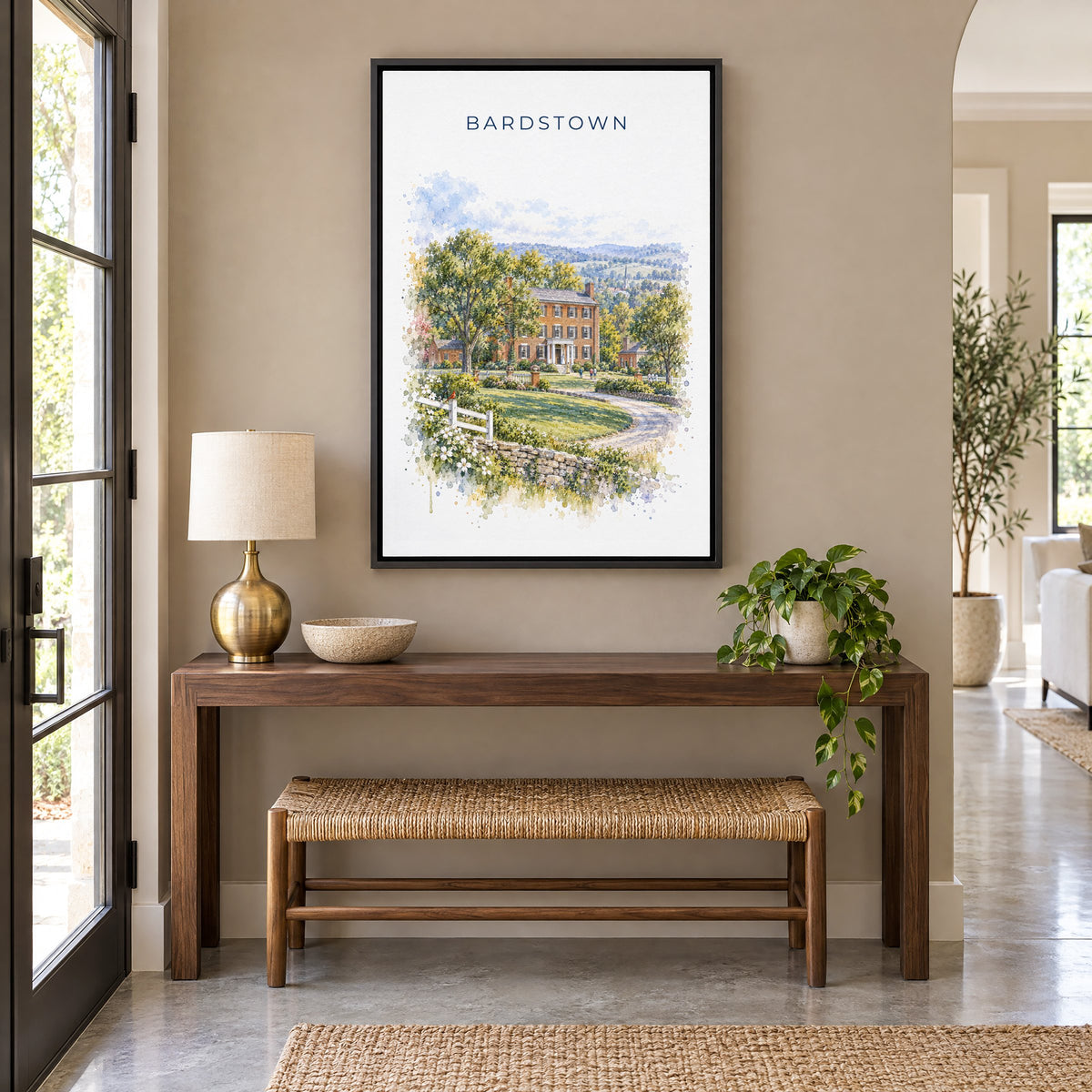 Bardstown, Kentucky watercolor print as a black floater canvas above a walnut console and woven bench in an entryway