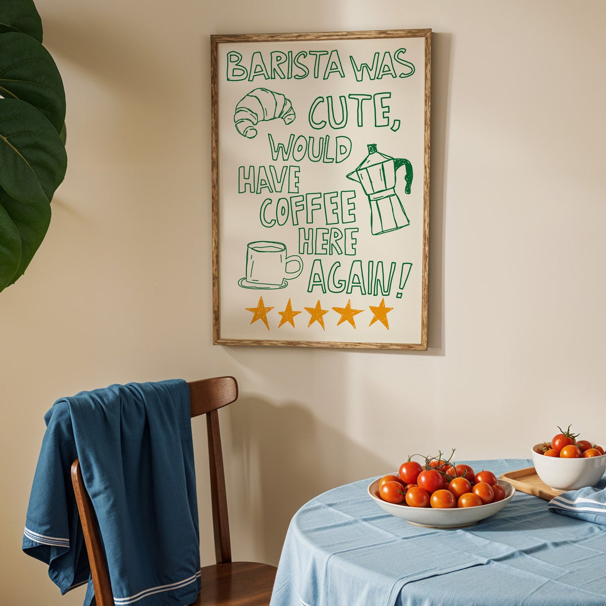 Green outline barista print in an oak frame above a blue linen table with ripe tomatoes