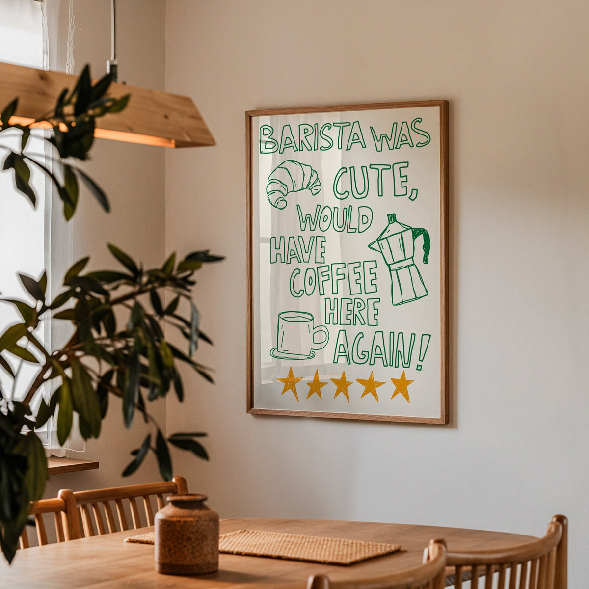 Green outline barista print in a walnut frame above a dining table beside an olive tree