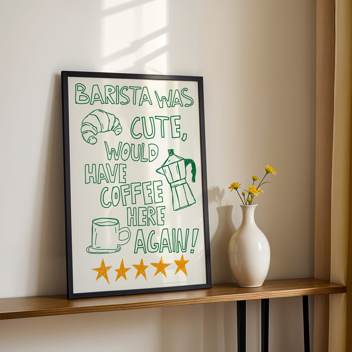 Green outline barista print in a black frame on a console table with yellow daisies
