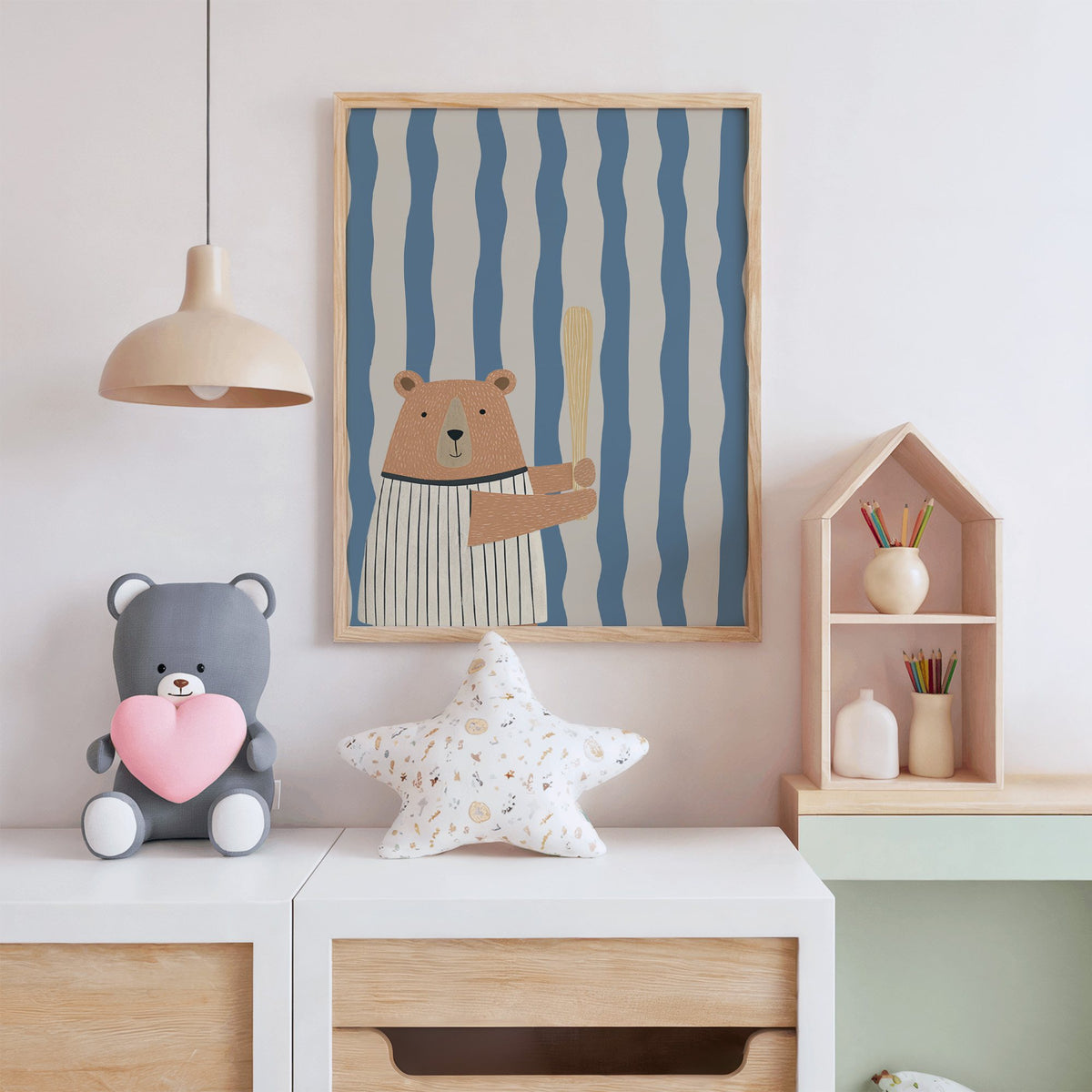 Baseball bear blue stripe nursery print in an oak frame above a white dresser with a star pillow and house shelf