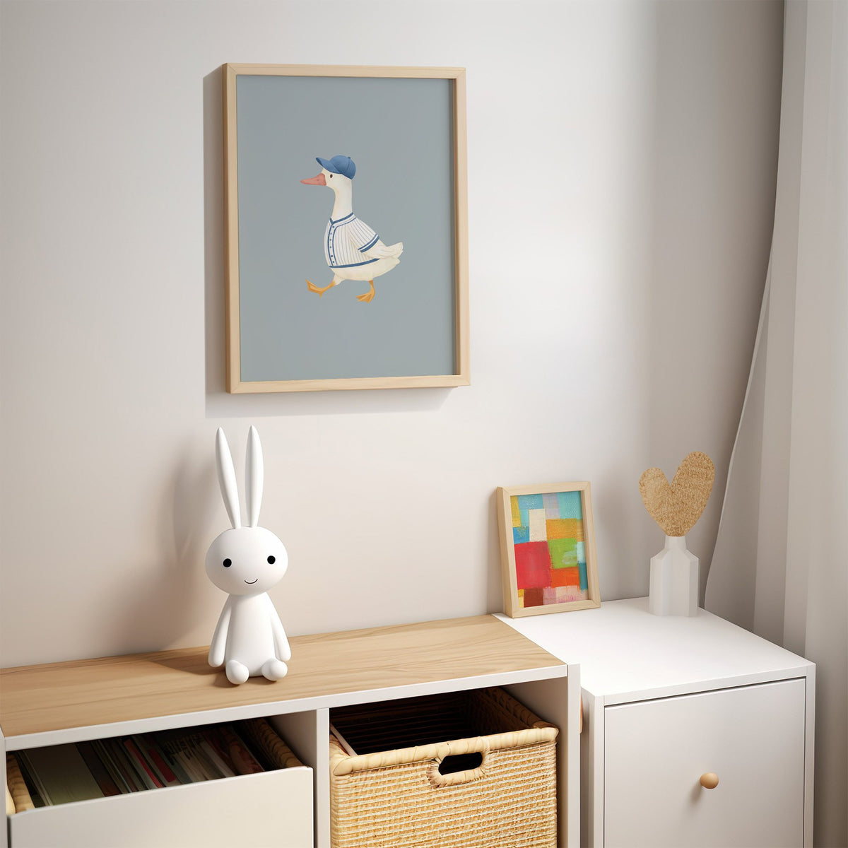 Baseball bird blue cap nursery print in an oak frame above a kids cubby shelf with a woven basket and bunny lamp