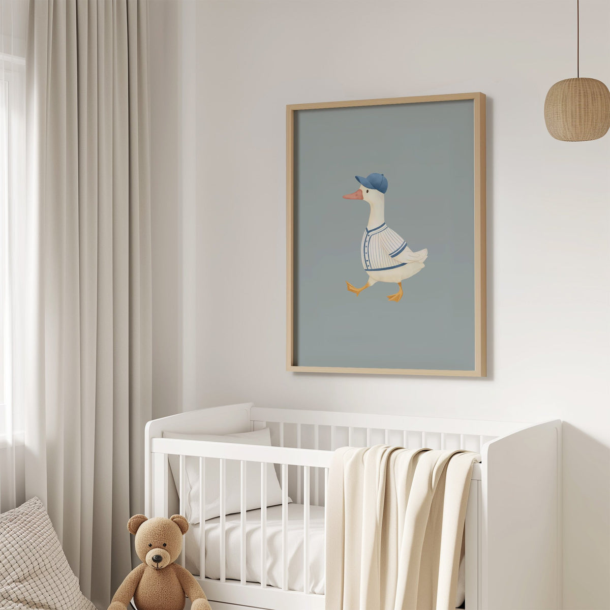 Baseball bird blue cap nursery print in an oak frame above a white crib with a teddy bear