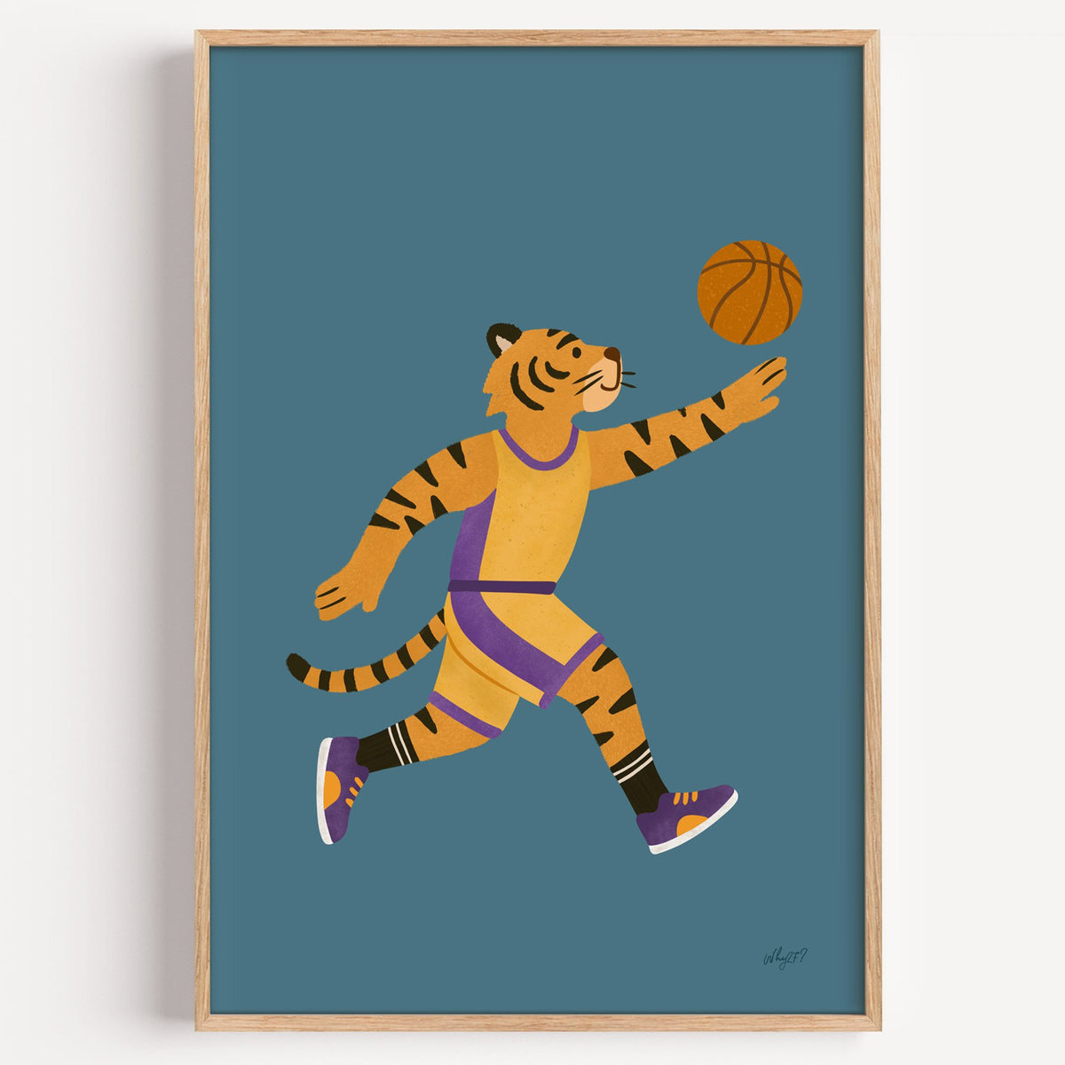 Tiger playing basketball nursery print in a light oak frame on a plain white wall