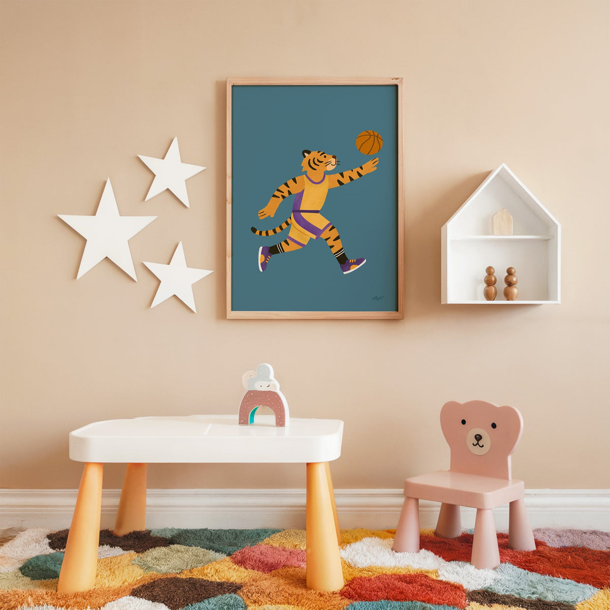 Tiger playing basketball nursery print in an oak frame on a peach wall above a kids table with wall stars