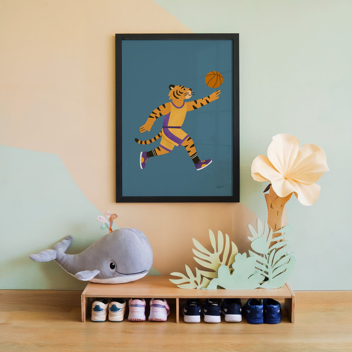Tiger playing basketball nursery print in a black frame on a mint and peach wall above a whale plush