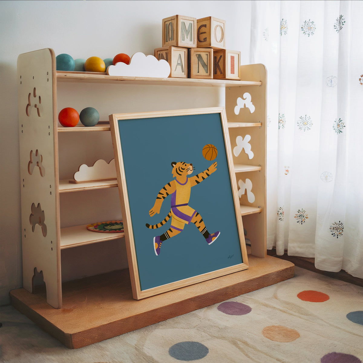 Tiger playing basketball nursery print in an oak frame leaning on a toy shelf with wooden letter blocks