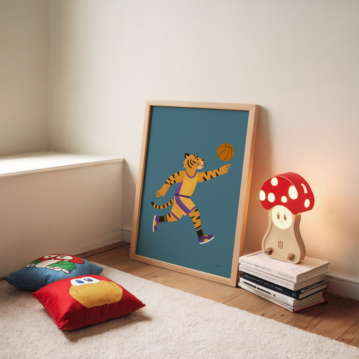 Tiger playing basketball nursery print in an oak frame leaning on a rug beside a mushroom lamp and floor cushions