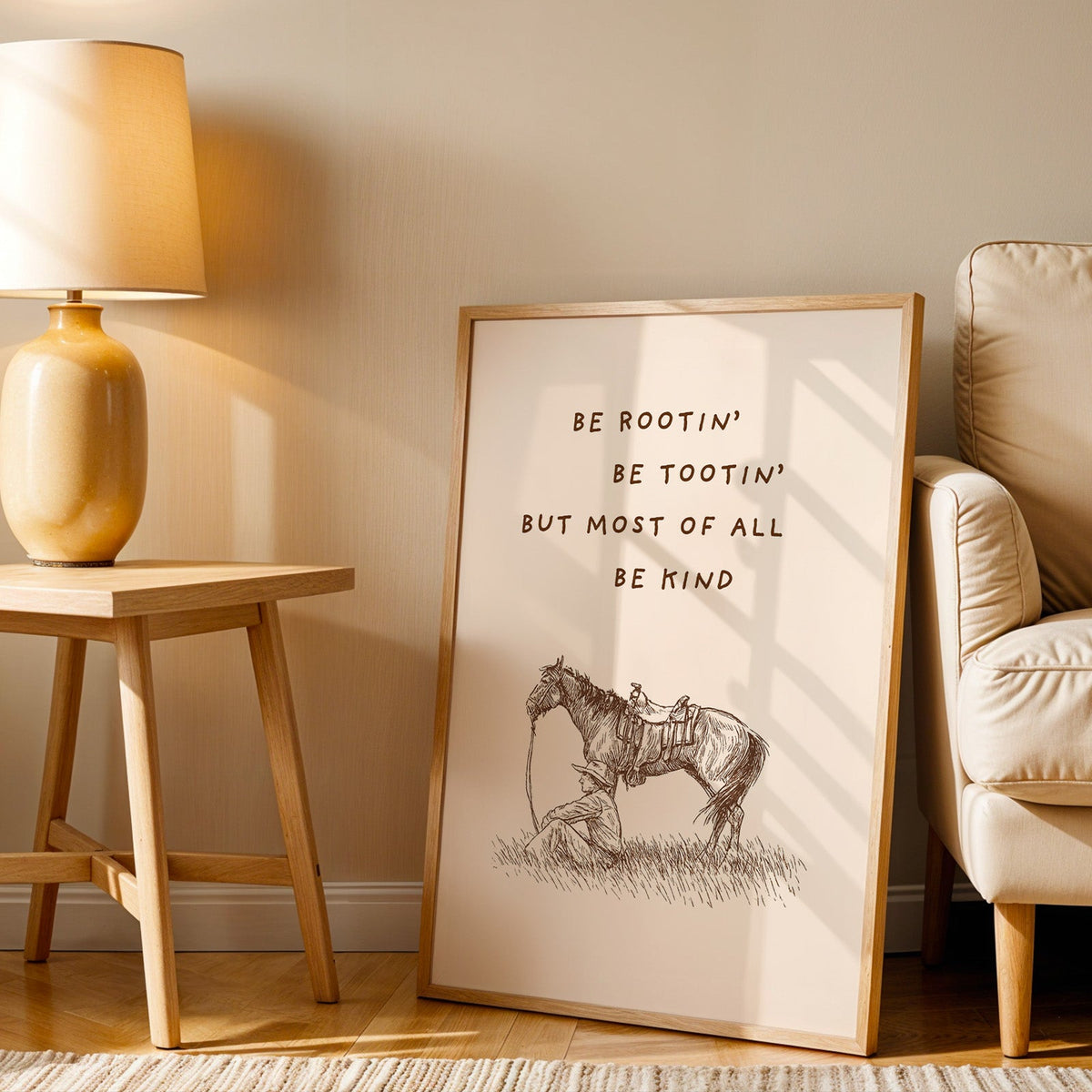 Be Rootin Be Tootin cream print in an oak frame beside an amber ceramic lamp