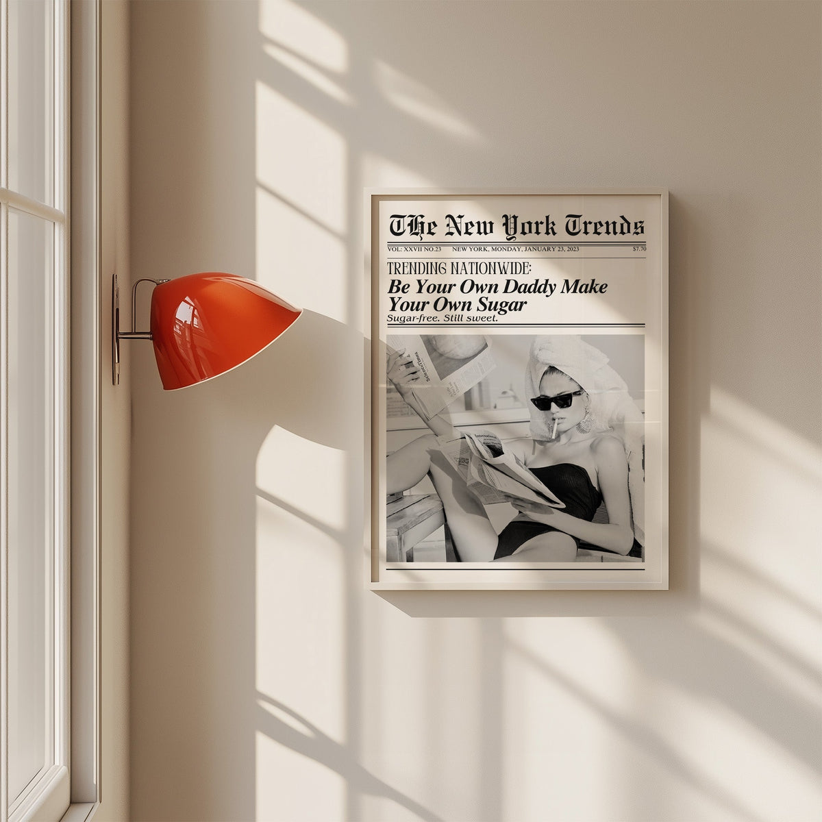 Woman reading newspapers on rooftop mock front page print in a white frame on a sunlit wall beside a red sconce