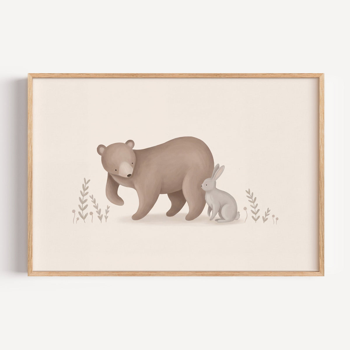 Brown bear and grey bunny in a meadow nursery print in a light oak frame on a plain white wall