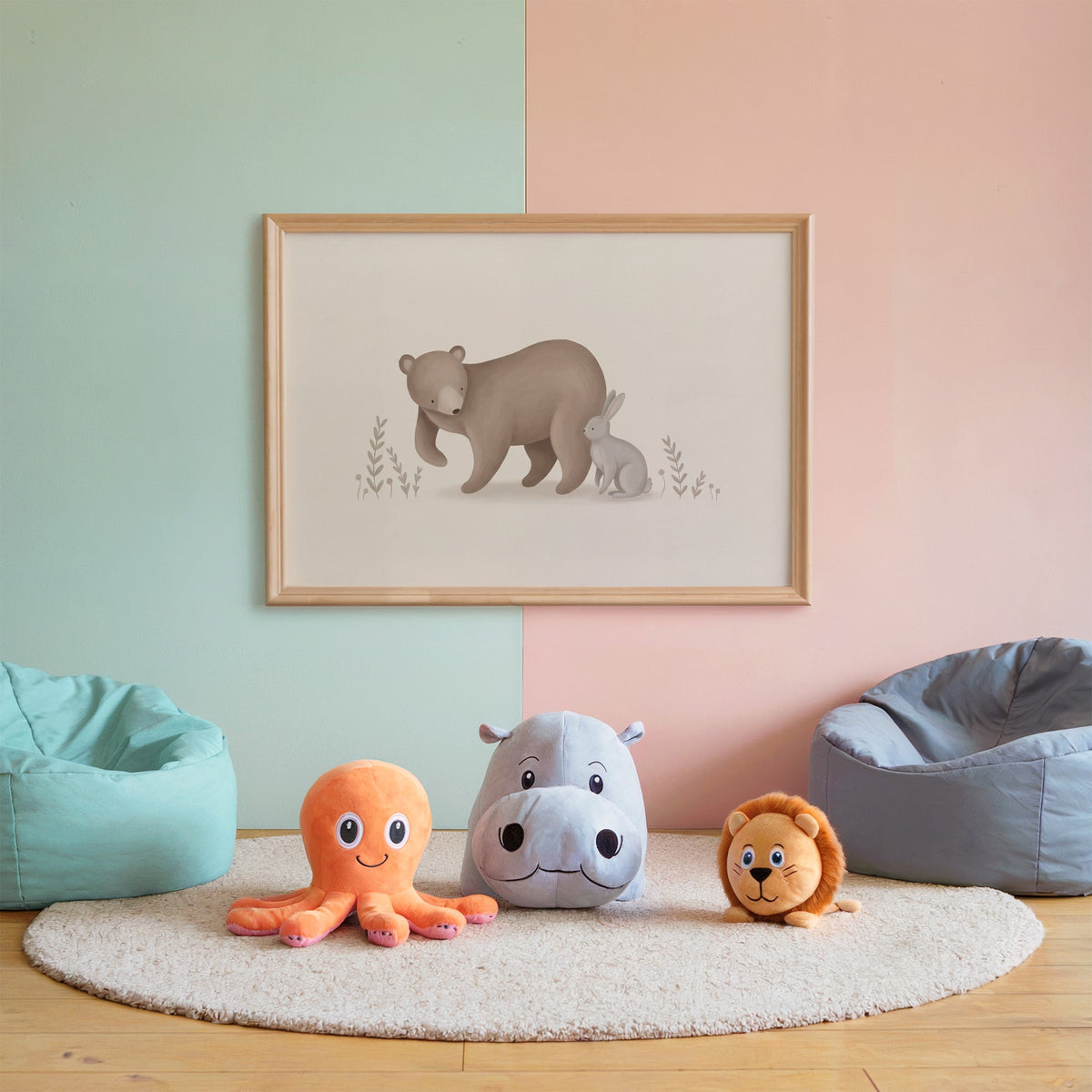 Brown bear and grey bunny in a meadow nursery print in an oak frame on a mint and pink wall above plush toys