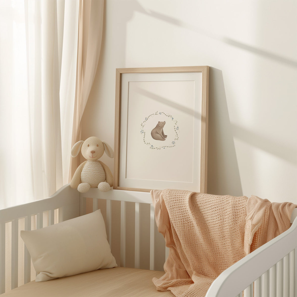 Bear cub in a blue flower wreath nursery print shown in an oak frame with a white mat on a crib rail