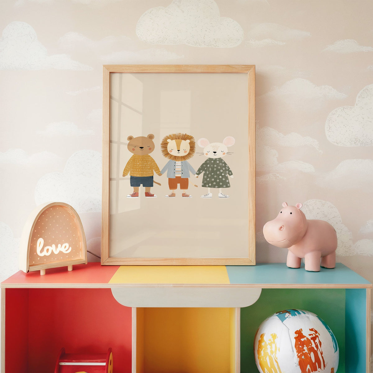 Three friends holding hands nursery print in an oak frame on a rainbow toy shelf against cloud wallpaper