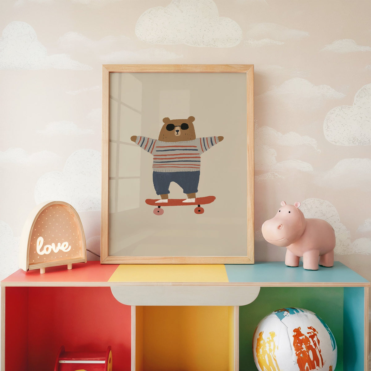 Skateboard bear striped sweater nursery print in an oak frame on a rainbow toy shelf against cloud wallpaper