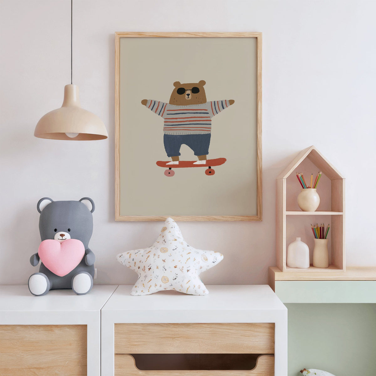 Skateboard bear striped sweater nursery print in an oak frame above a white dresser with a star pillow and house shelf