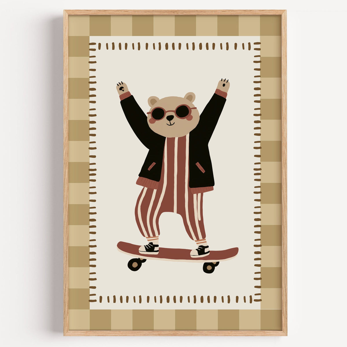 Skateboard bear checker border nursery print in a light oak frame on a plain white wall