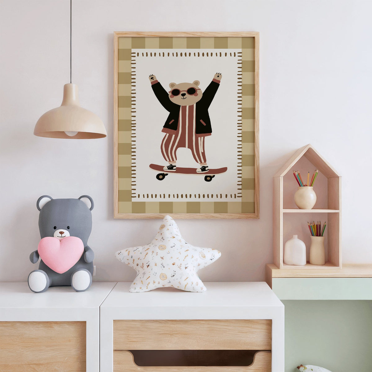 Skateboard bear checker border nursery print in an oak frame above a white dresser with a star pillow and house shelf