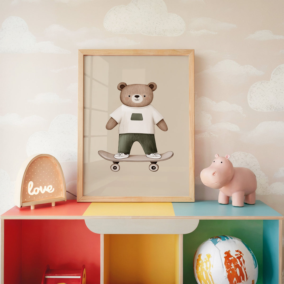 Skateboard bear white tee nursery print in an oak frame on a rainbow toy shelf against cloud wallpaper