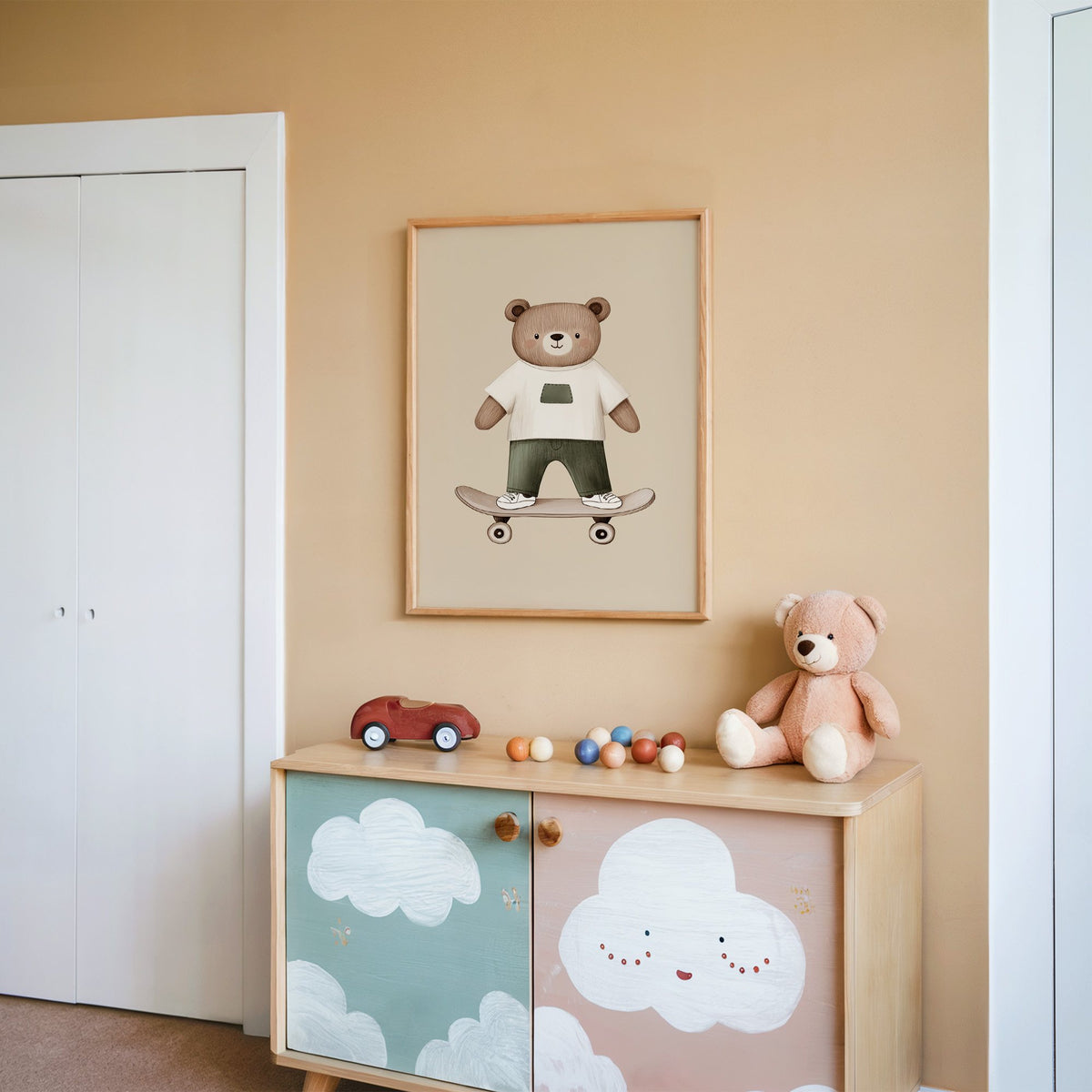 Skateboard bear white tee nursery print in an oak frame on a peach wall above a cloud-painted cabinet