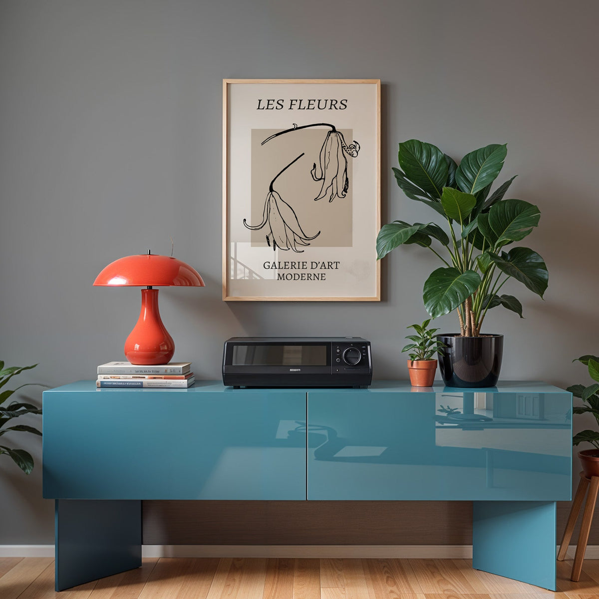Drooping lily sketch on beige block botanical print in a light oak frame above a teal sideboard with a red mushroom lamp