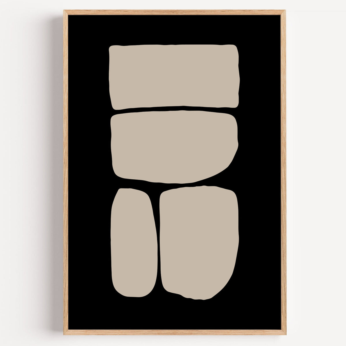 Beige four stacked stones on black minimalist print in a light oak frame on a plain white wall