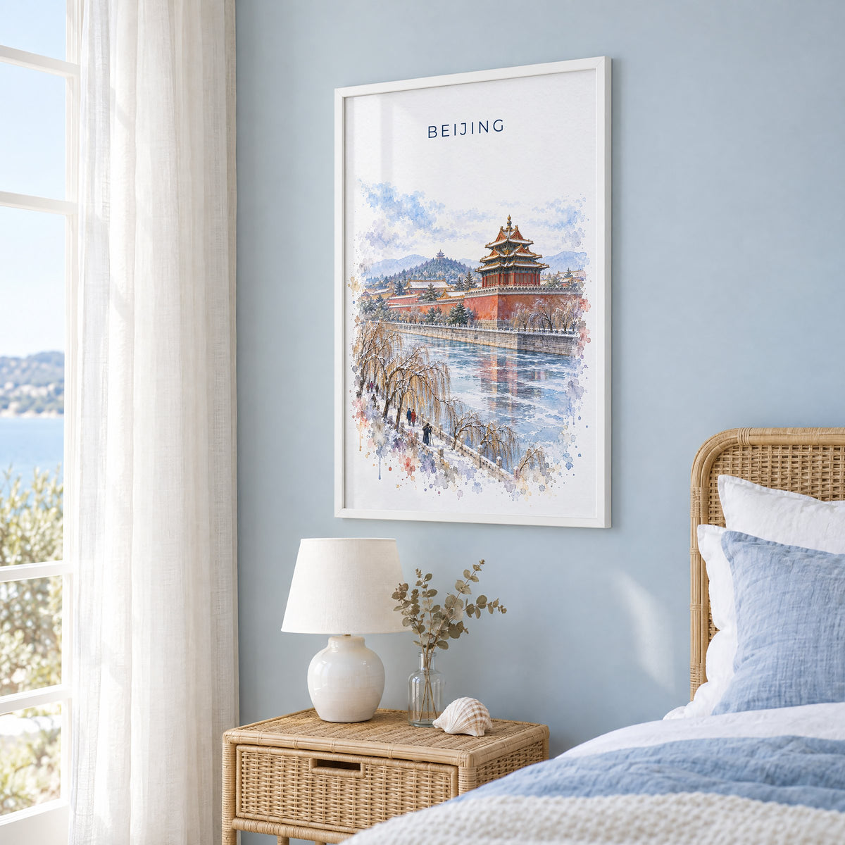 Beijing watercolor print in a white frame on a pale blue wall beside a rattan bed in a coastal bedroom
