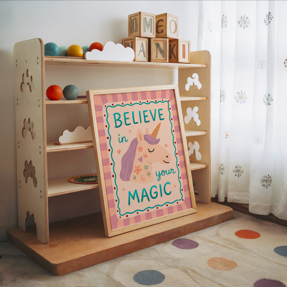 Believe in your magic unicorn nursery print in an oak frame leaning on a toy shelf with wooden letter blocks
