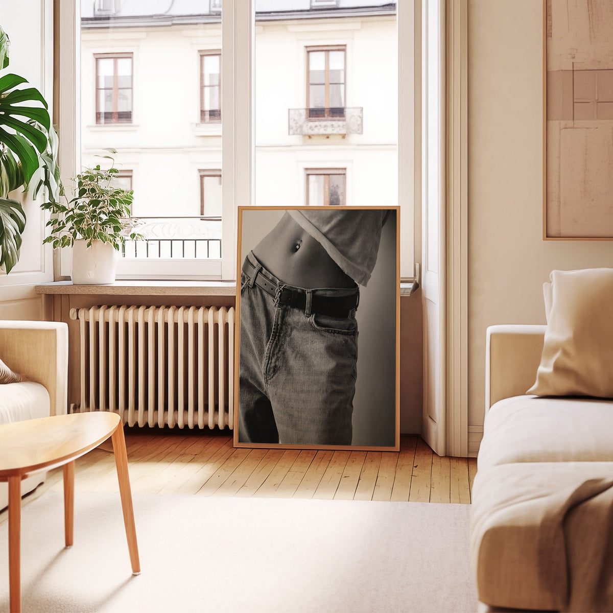 Belly piercing above faded jeans and belt buckle print in an oak frame leaning by a French window in a living room