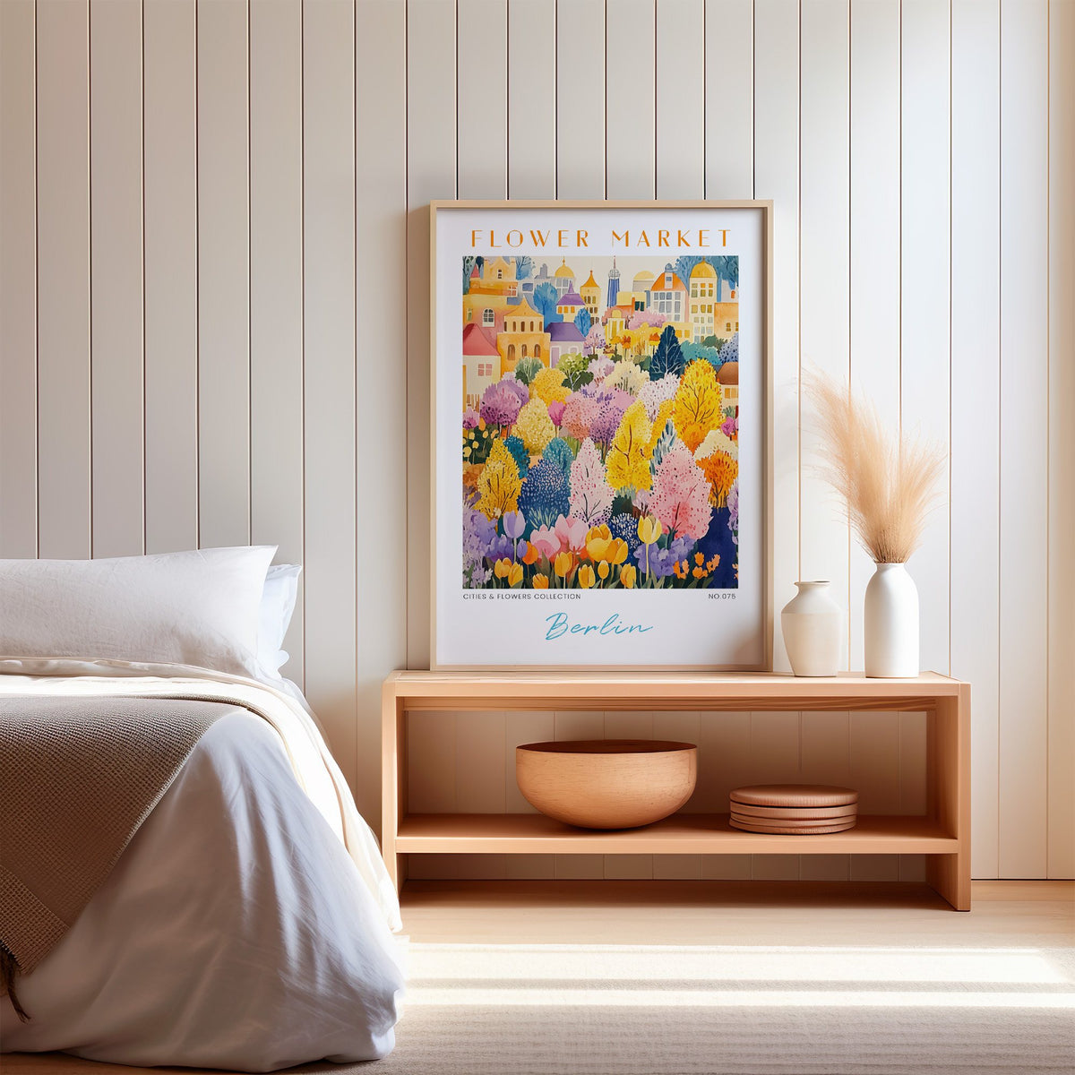 Berlin flower market print in an oak frame on a wood bench against a white shiplap bedroom wall with pampas grass