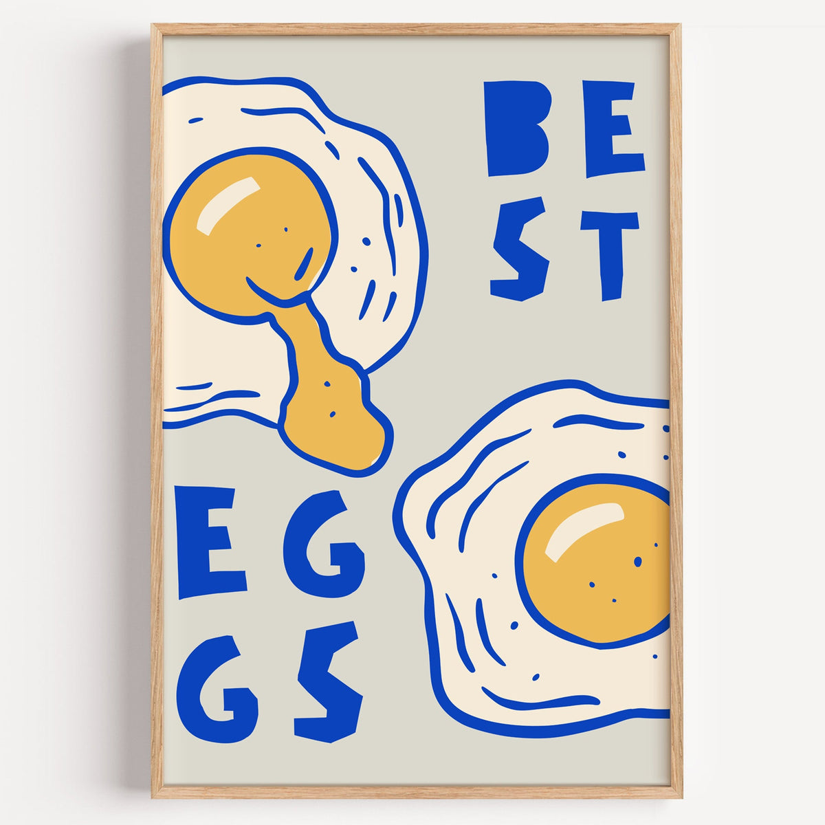 Best Eggs cobalt type print in a light oak frame on a plain white wall