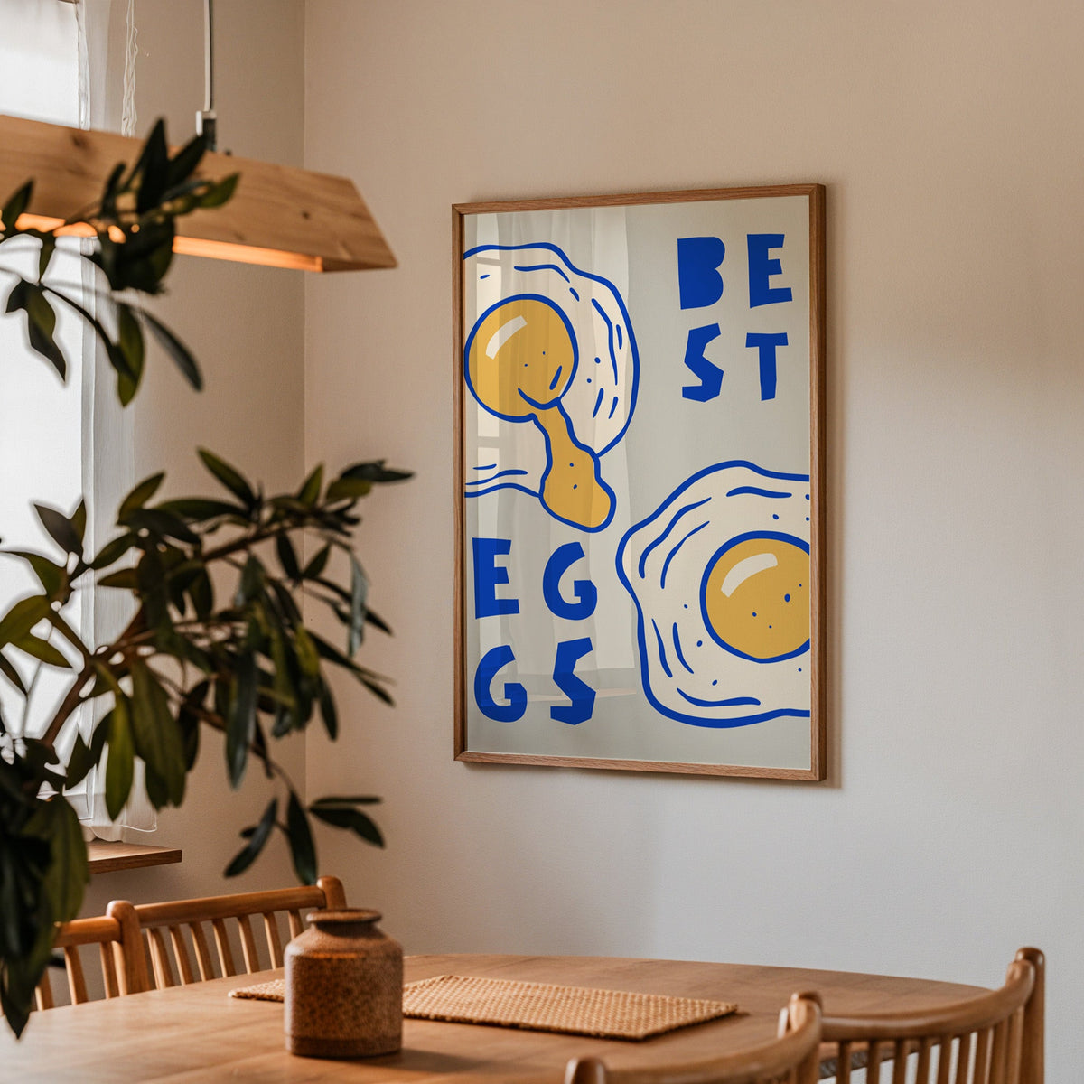 Best Eggs print in a walnut frame above a dining table with olive branches