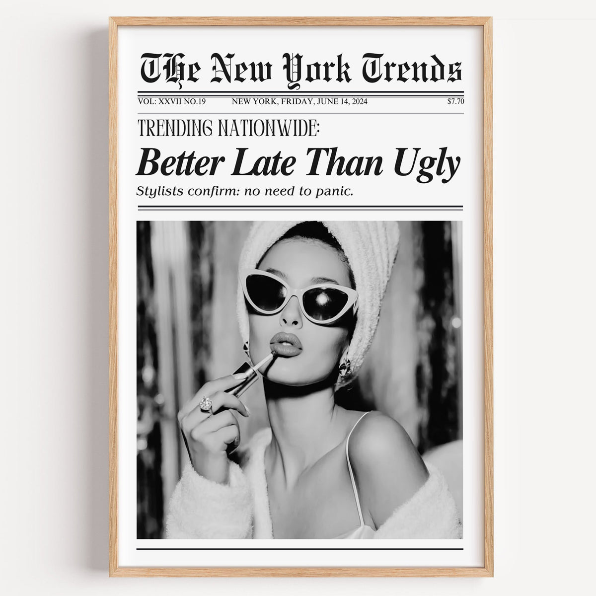 Woman applying lipstick mock newspaper print in a light oak frame on a plain white wall