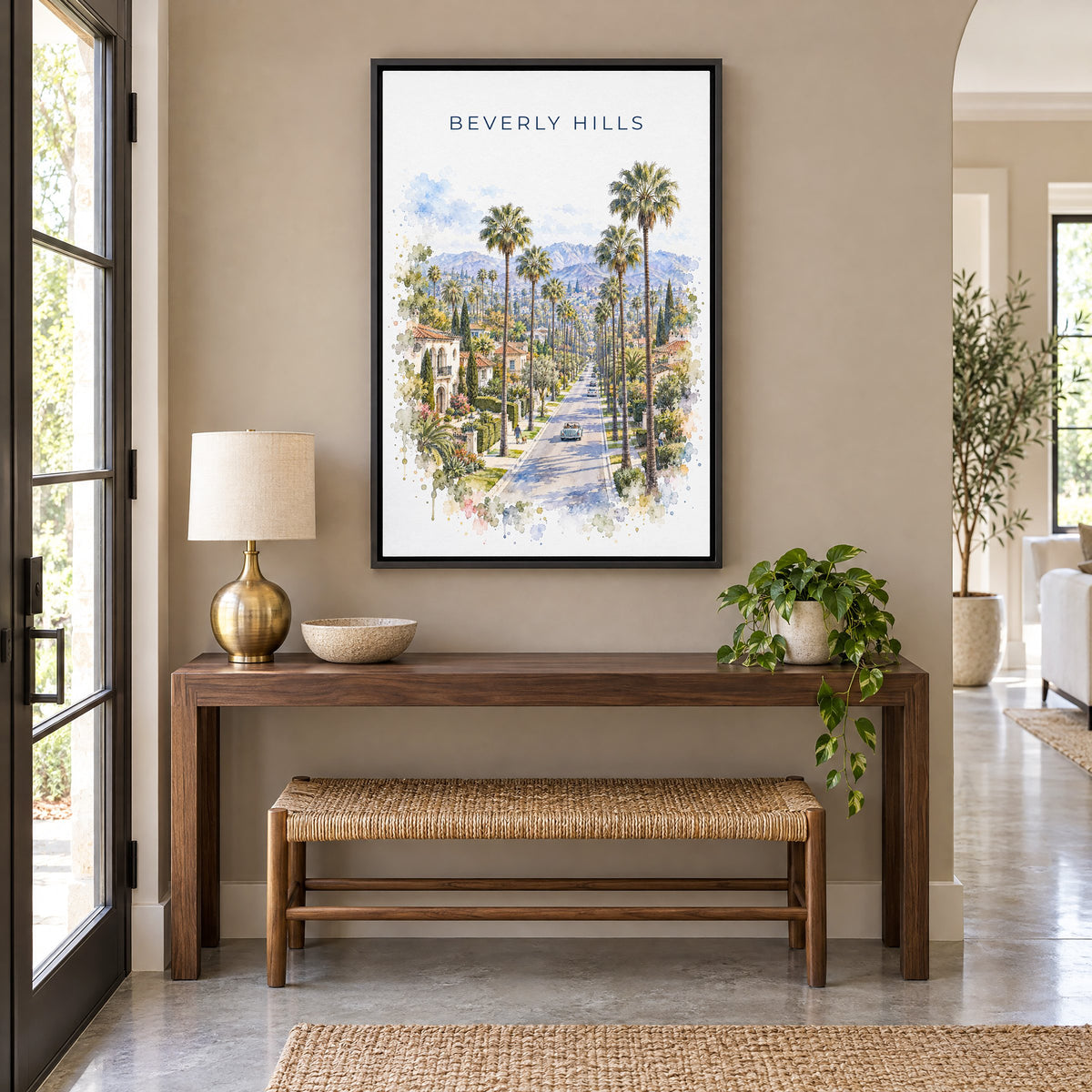 Beverly Hills watercolor print as a black floater canvas above a walnut console and woven bench in an entryway