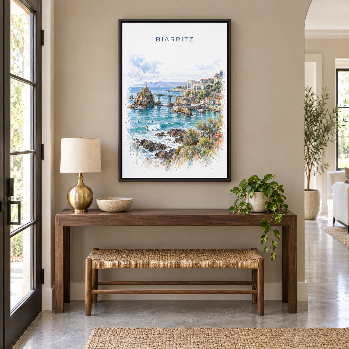 Biarritz watercolor print as a black floater canvas above a walnut console and woven bench in an entryway