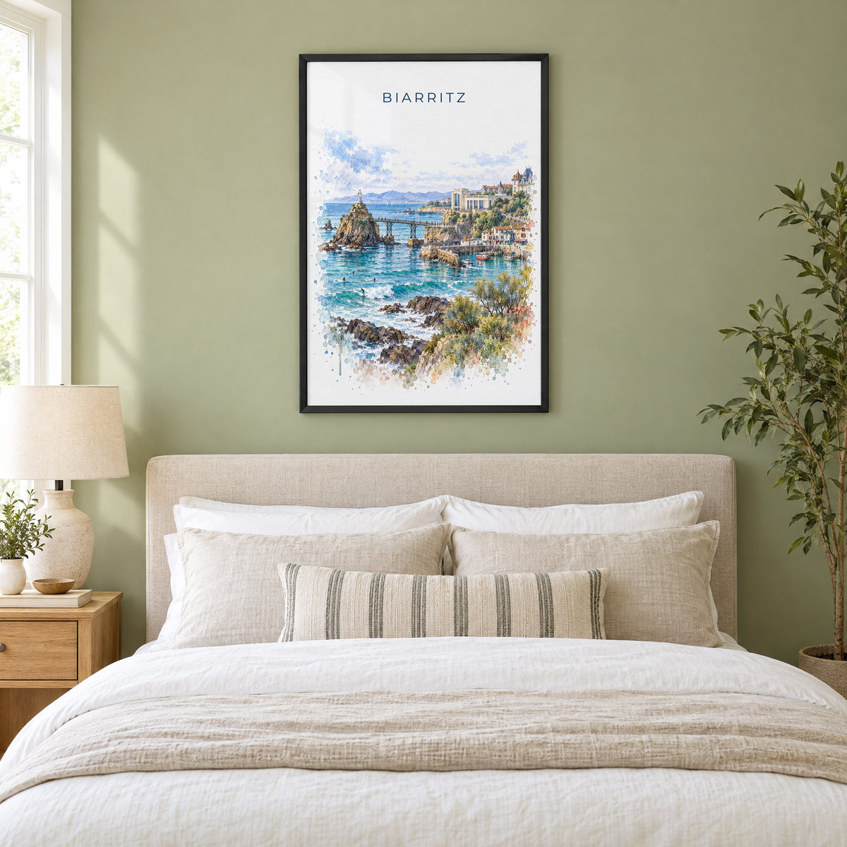 Biarritz watercolor print in a black frame above an upholstered headboard in a sage green bedroom