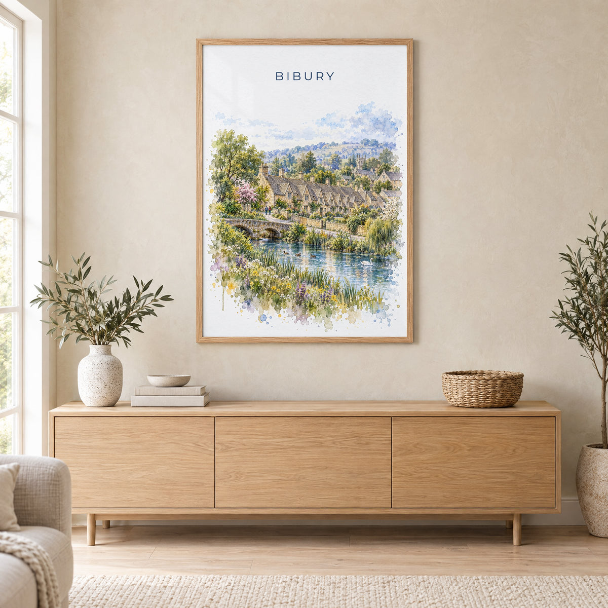 Bibury watercolor print in an oak frame above a light wood sideboard in a Scandinavian living room