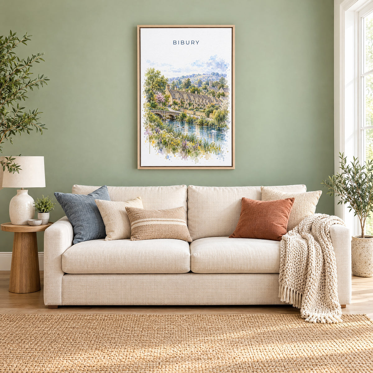 Bibury watercolor print as a natural floater canvas above a cream linen sofa on a sage green wall