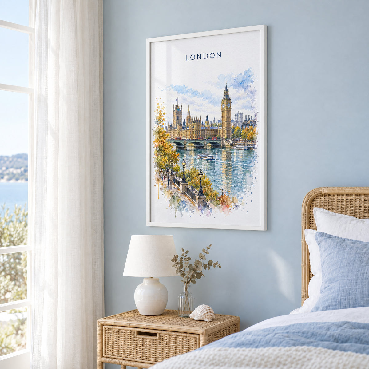 Big Ben watercolor print in a white frame on a pale blue wall beside a rattan bed in a coastal bedroom