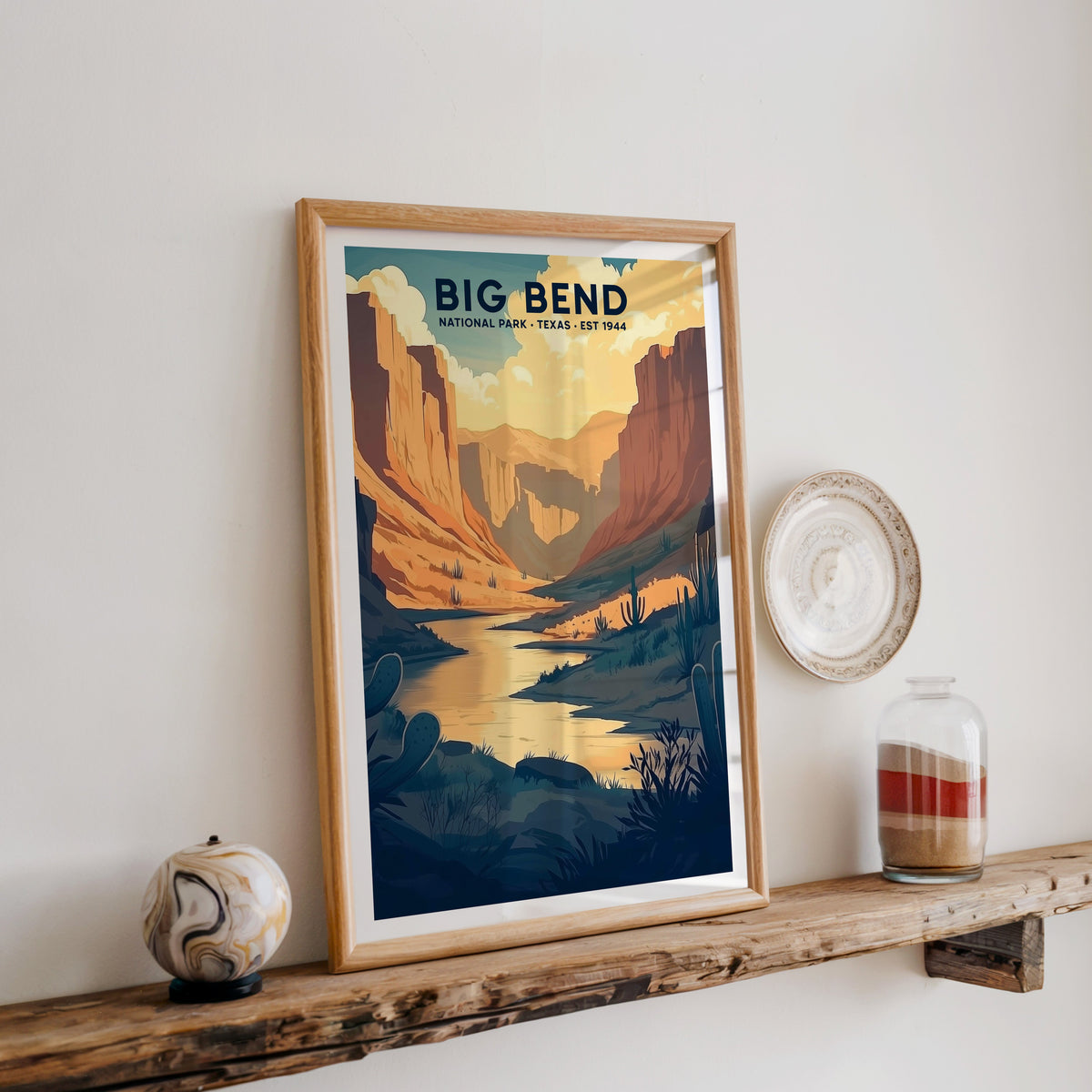 Big Bend National Park print in an oak frame on a rustic wood shelf with ceramics and a sand jar