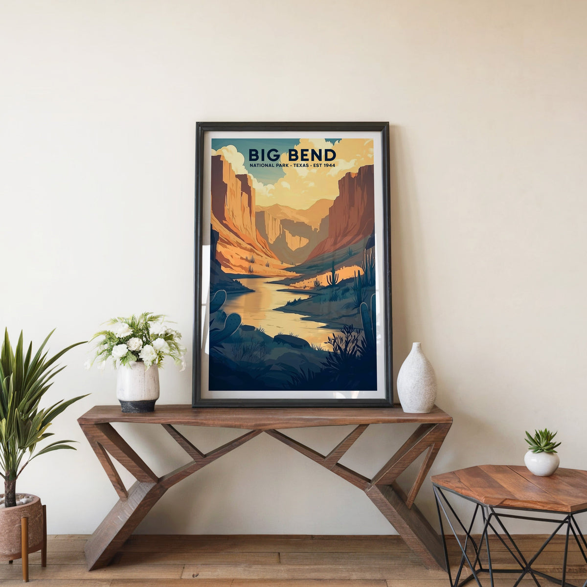 Big Bend poster in a black frame on an entryway console table beside white flowers and a yucca