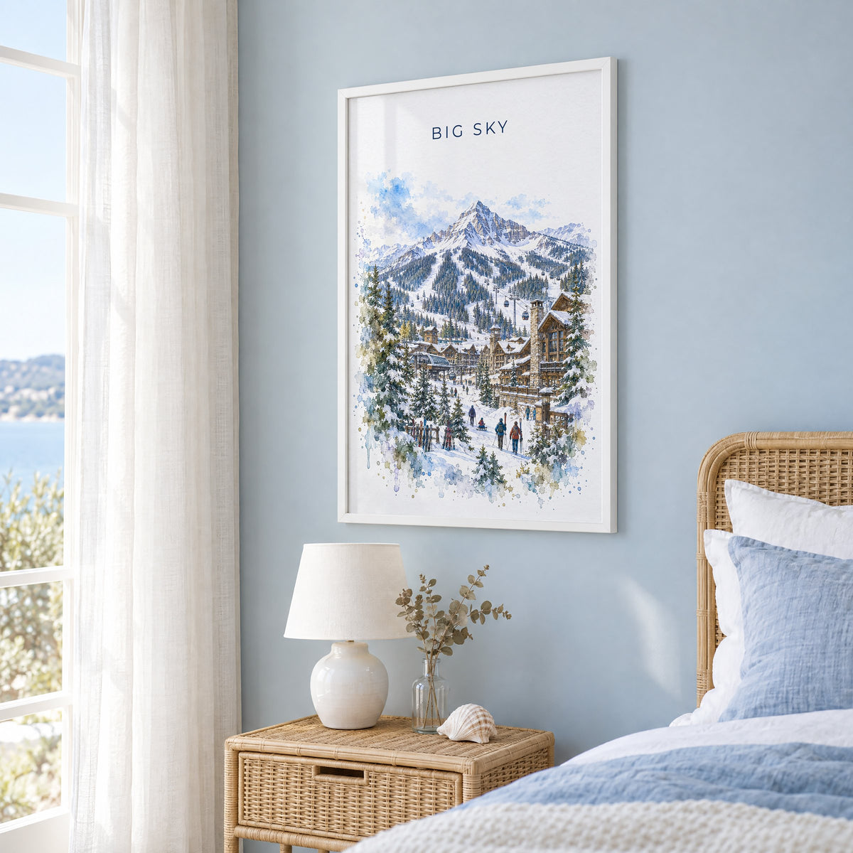 Big Sky watercolor print in a white frame on a pale blue wall beside a rattan bed in a coastal bedroom