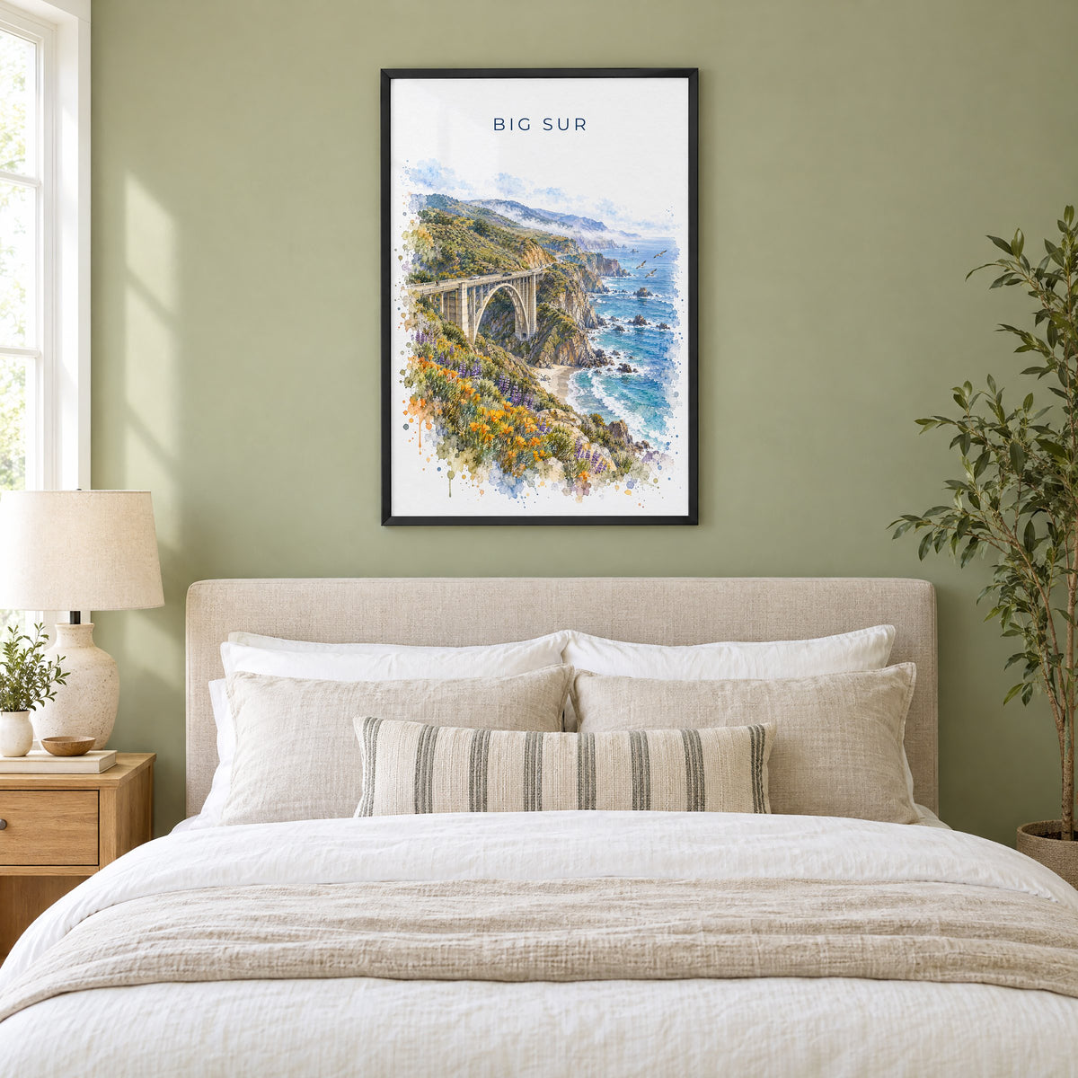 Big Sur watercolor print in a black frame above an upholstered headboard in a sage green bedroom