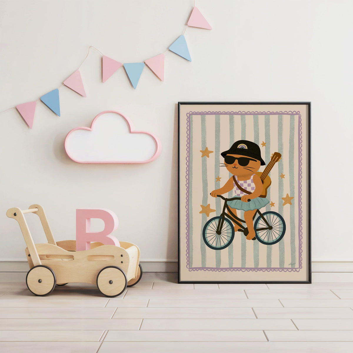 Orange cat on bicycle with ukulele nursery print in a black frame under pastel bunting by a wooden baby walker